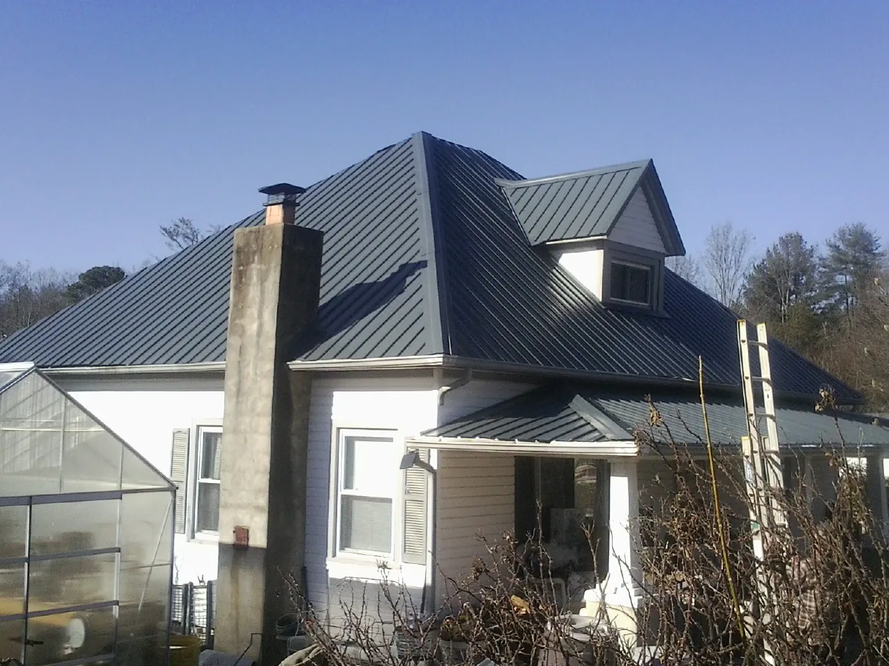 Dark blue standing seam metal roof on a white farmhouse with dormer — Slate & Tile Roof Repair by Roofing Brothers in Hysham