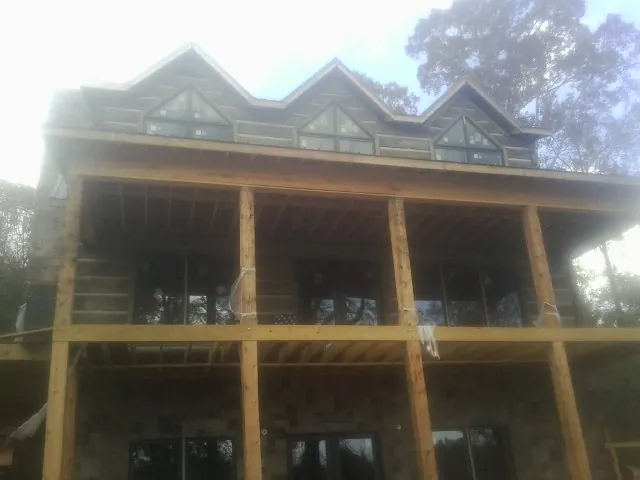 Dormers and porch framing on a large log home under construction — Roof Coating work by our crew in Hysham