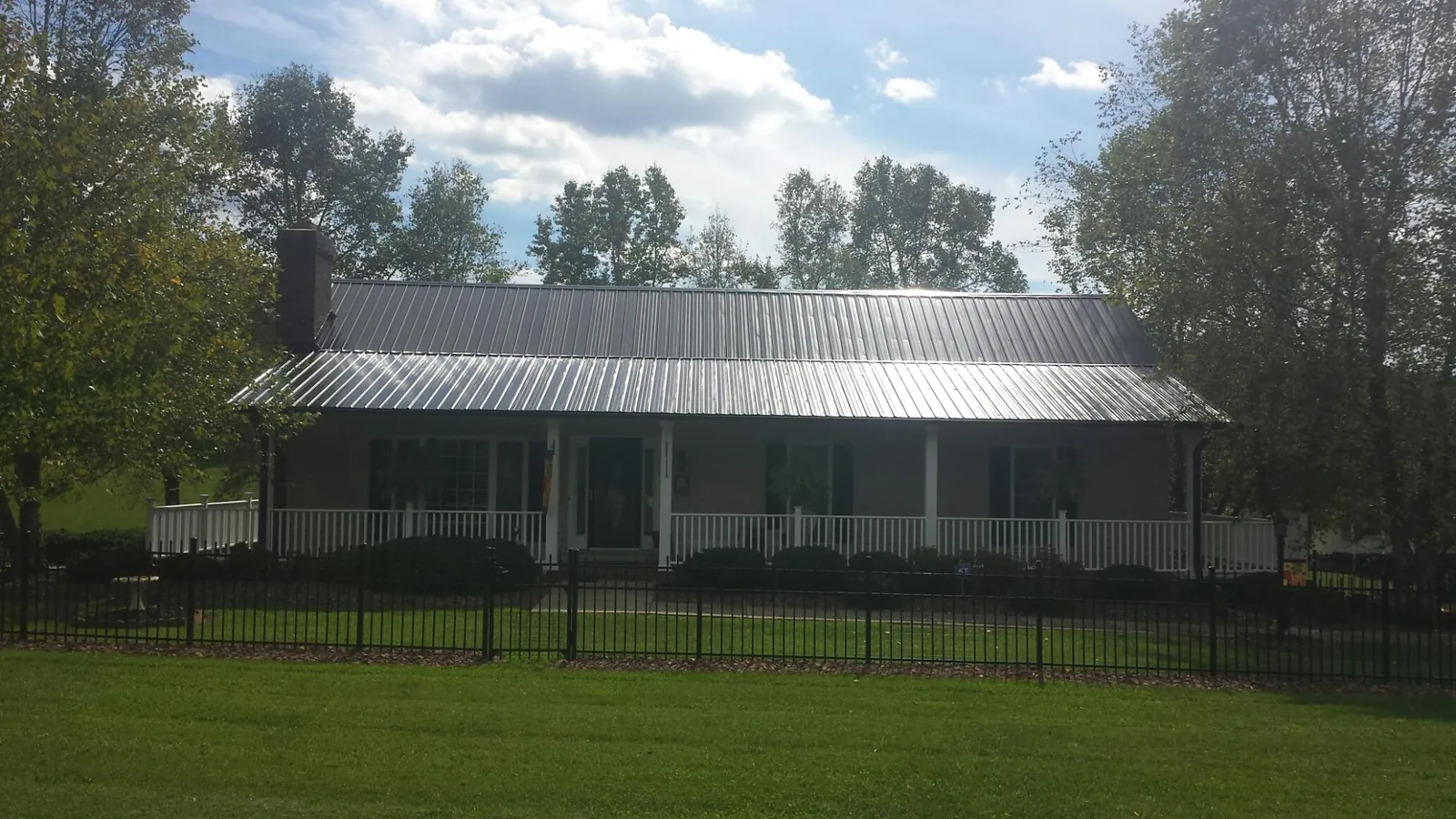 Gray metal roof on a brick ranch with a full width front porch — Gutter Guard Installation work by our crew in Hysham