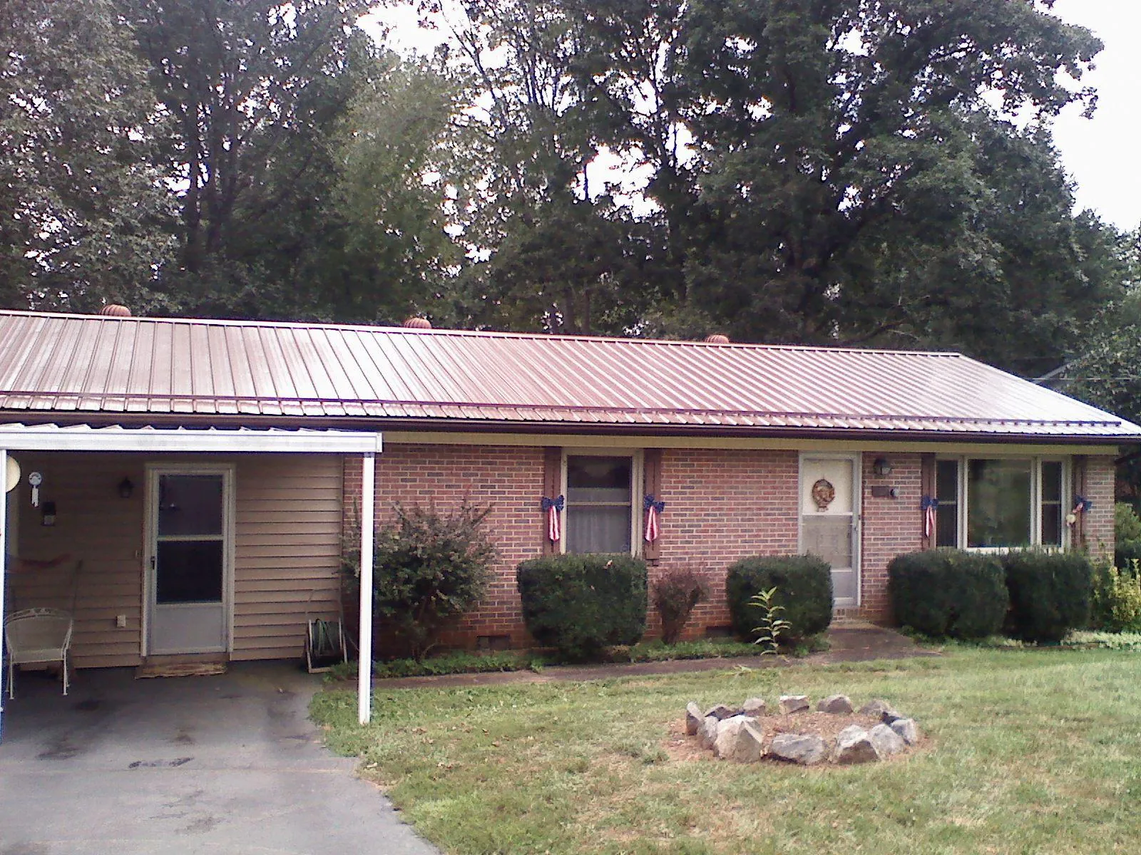 Bronze metal roof and carport on a brick ranch home — Roof Repair work by our crew in Hysham