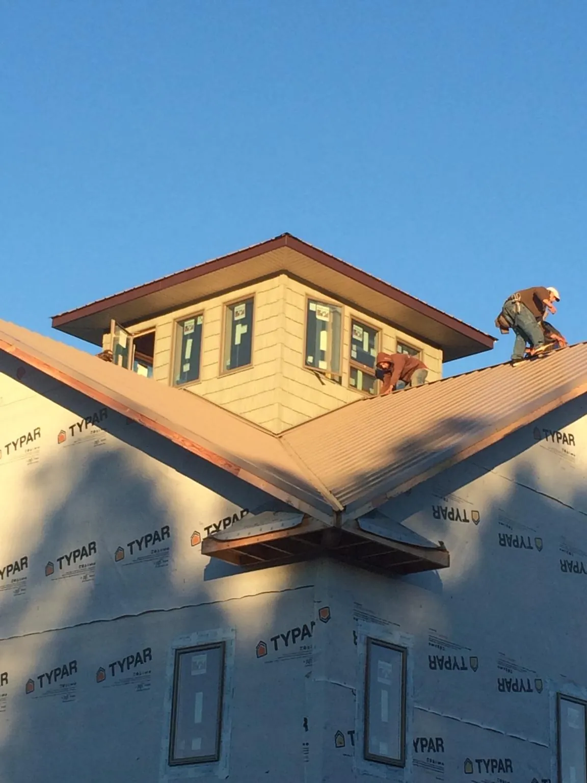 Roofers working around a rooftop cupola on a new metal roof at sunset — Roof Waterproofing in Hysham by Roofing Brothers